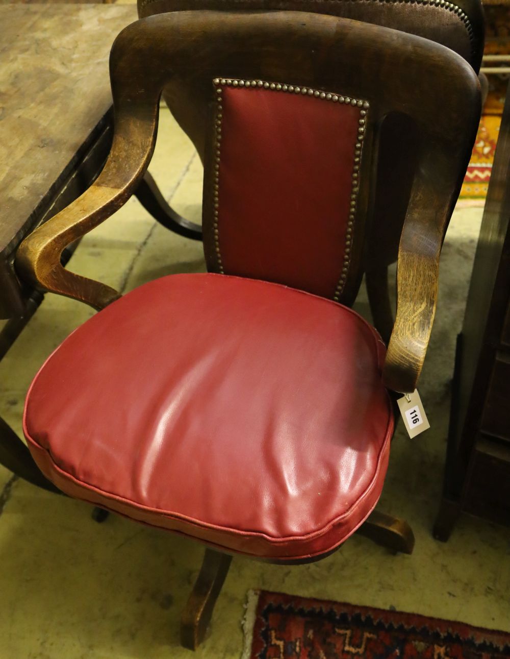 A 1920s oak swivel desk chair, the back and seat cushion covered in red hide, width 63cm, depth 50cm, height 94cm